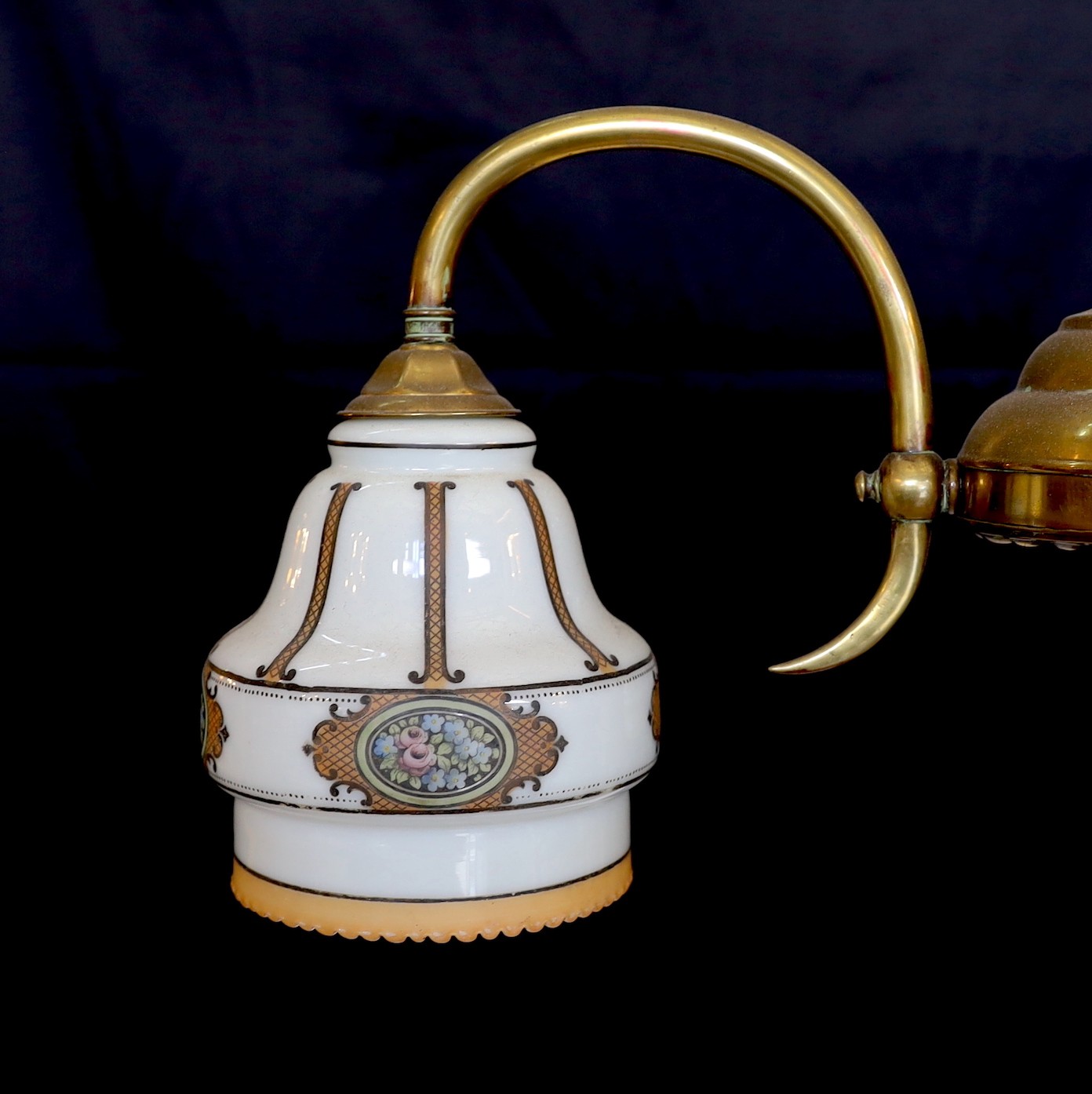 An early 20th century English lacquered brass light fitting with three stencilled opaque glass shades, height 65cm. width 50cm